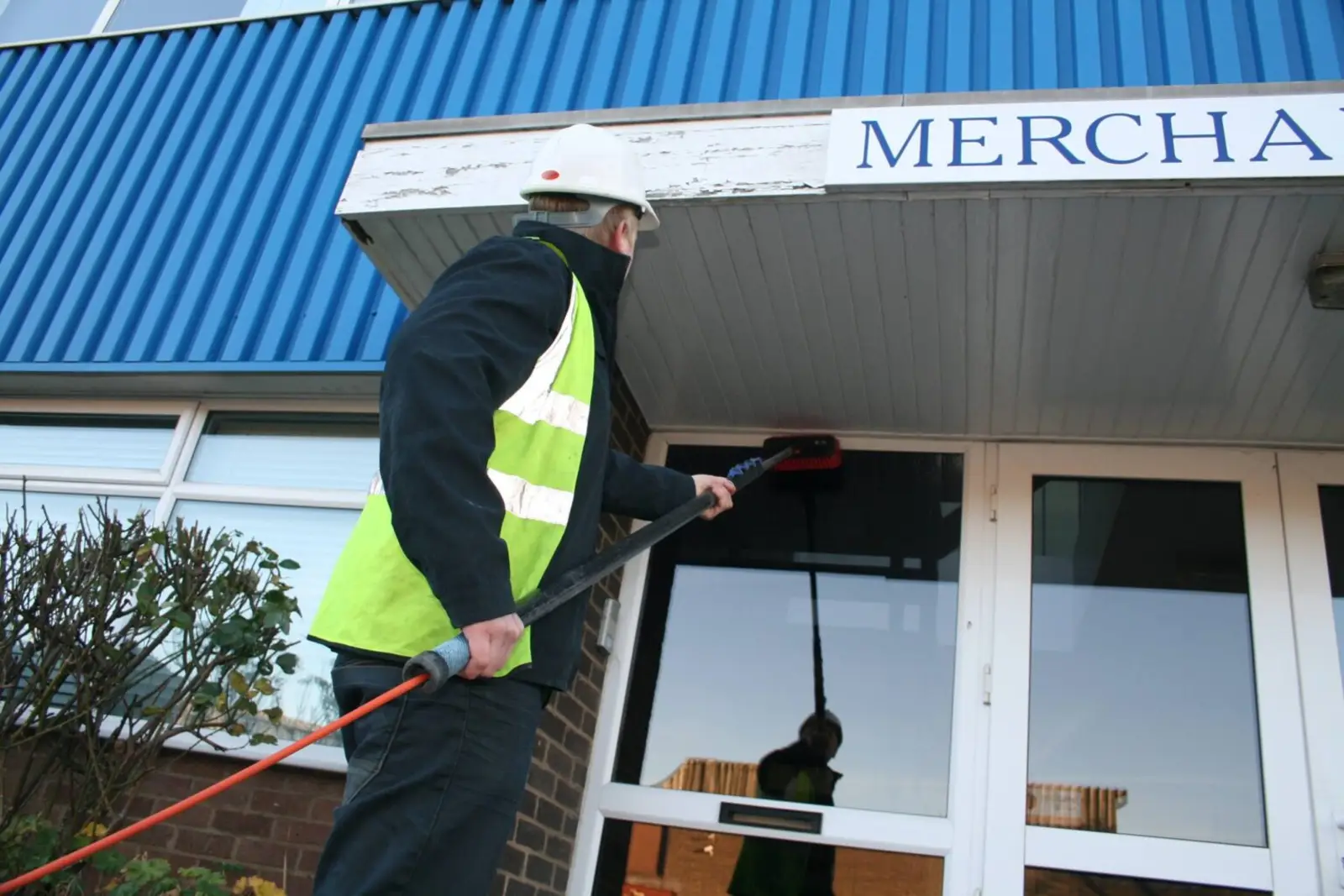 Pure Flex operator cleaning commercial windows with a water-fed pole